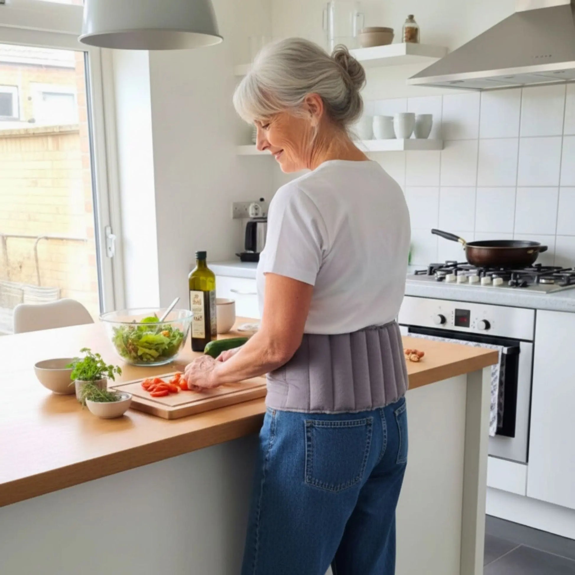 Lady at kitchen bench wearing her waist wheat bag while cooking